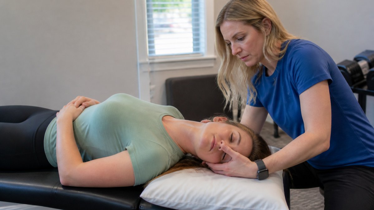 Physical therapist carefully positioning patient's head during Epley maneuver treatment in clinical setting with proper lighting